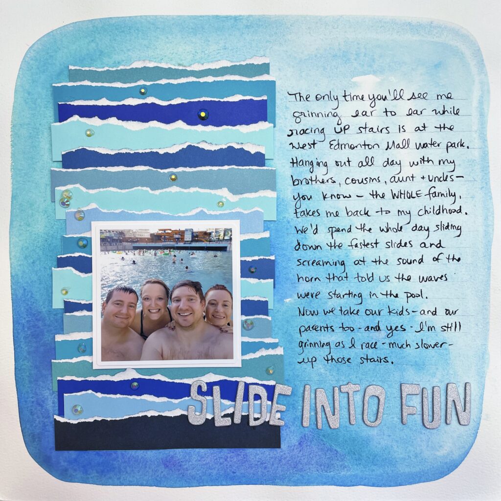 scrapbook layout with a blue watercolour background that has a title that says slide into fun. The layout has a photo of two men and two women at a waterpark. The layout has torn paper decorating it and journaling that talks about how running up stairs is fun at a waterpark.