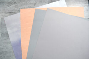 Sheets of pattern paper in lavender, peach, and gray.